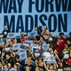 People hold blue Harris-Walz signs at a rally