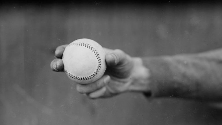 Black-and-white photo of a hand holding a baseball