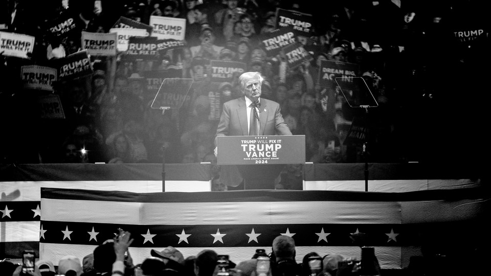 A black-and-white photo of Donald Trump standing at a podium, speaking to a crowd at Madison Square Garden.