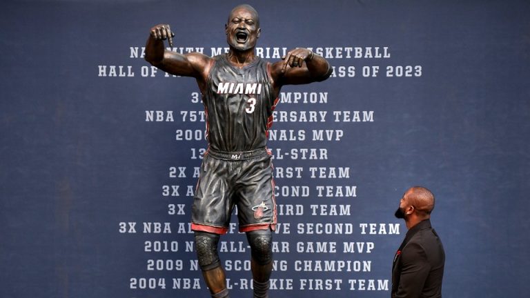 A color photo of Dwyane Wade looking up at the newly unveiled statue of himself.