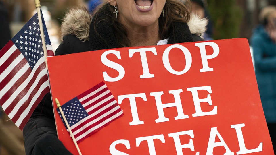 A woman yells while holding a "STOP THE STEAL" sign