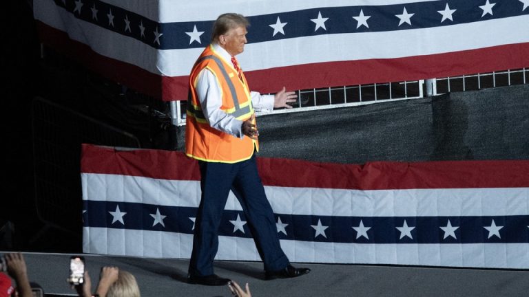 Donald Trump wears a garbage vest onstage