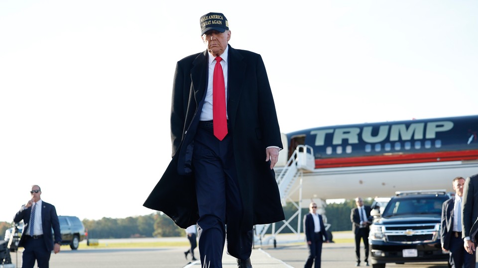 Donald Trump walks away from an airplane that reads "Trump."