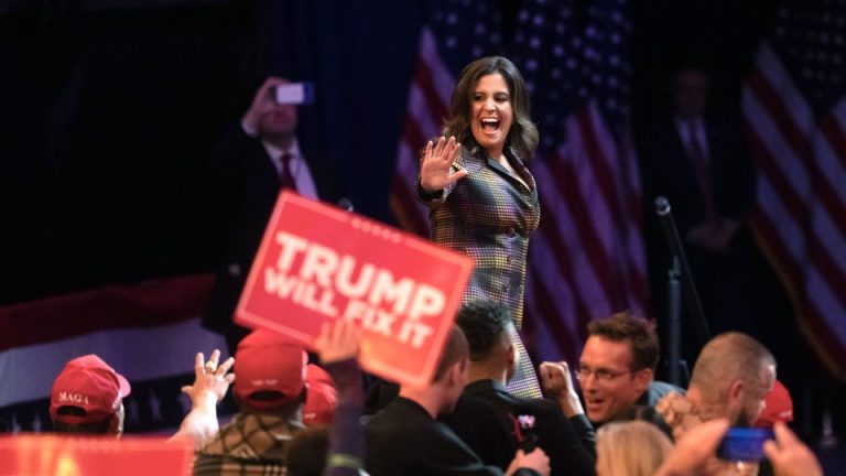 Rep. Elise Stefanik waves to the crowd, and a supporter holds up a "Trump Will Fix It" sign