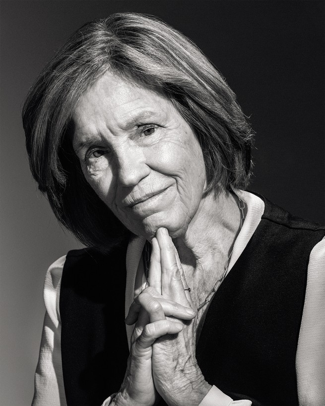 black-and-white photo of woman with head tilted and hands clasped with fingers resting under her chin