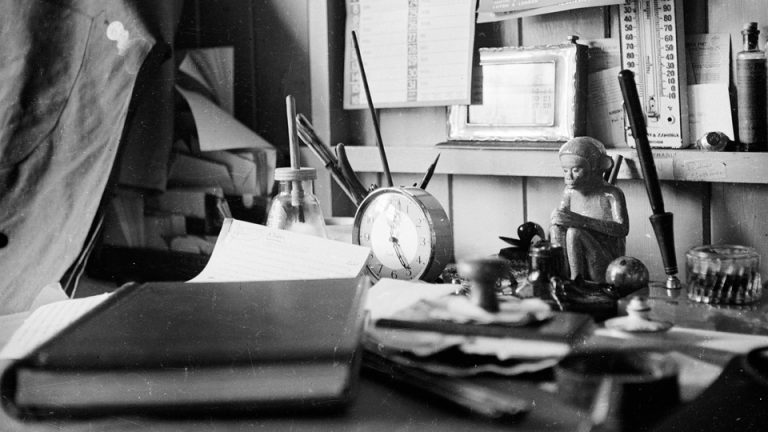 A black and white photo of a desk covered in personal effects.