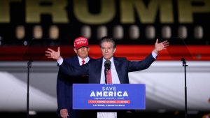 Donald Trump stands behind Mehmet Oz as Oz speaks at a podium