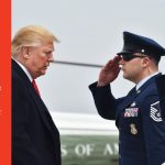 Donald Trump stands in front of two people in military uniform