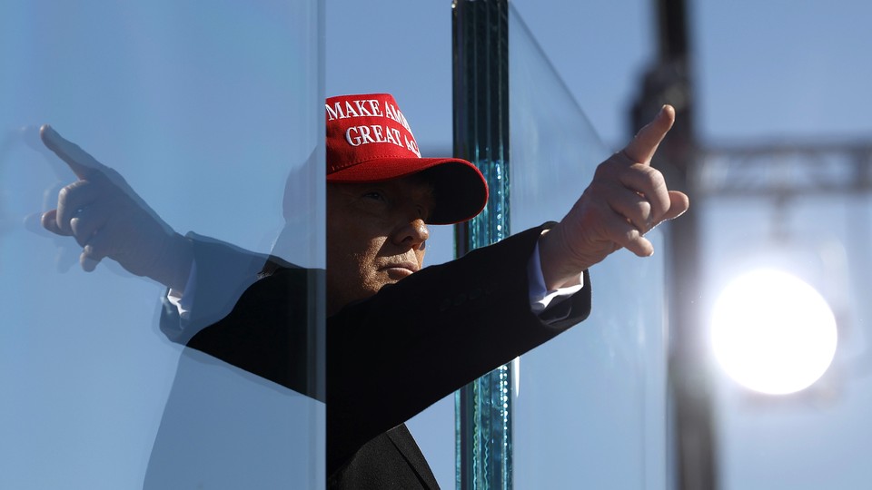 Donald Trump points his finger, and it reflects in the opposite direction on a pane of glass