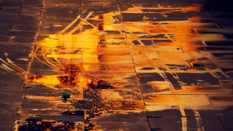 a puddle on the street, reflecting orange light