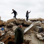 A mother and her son standing atop the rubble of a destroyed house in Tyre, Lebanon