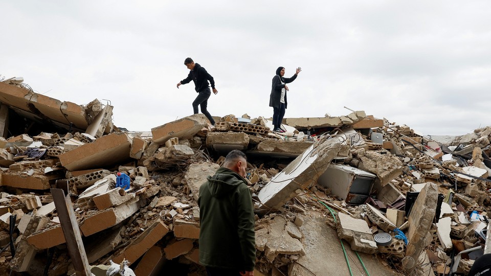 A mother and her son standing atop the rubble of a destroyed house in Tyre, Lebanon