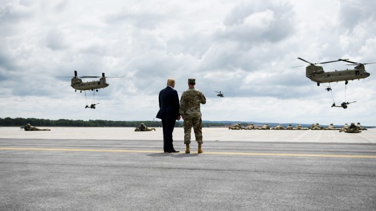 Photo of Donald Trump and an army major general watching two helicopters take off