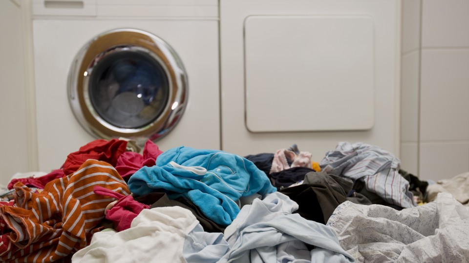 A pile of laundry in front of a washing machine