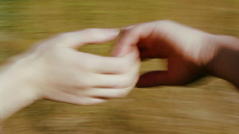 An interracial couple holds hands in a blurry image