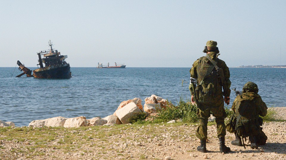 Soldiers point guns at the ocean