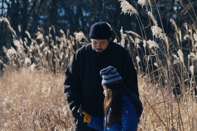 A man stands next to a young girl in a field