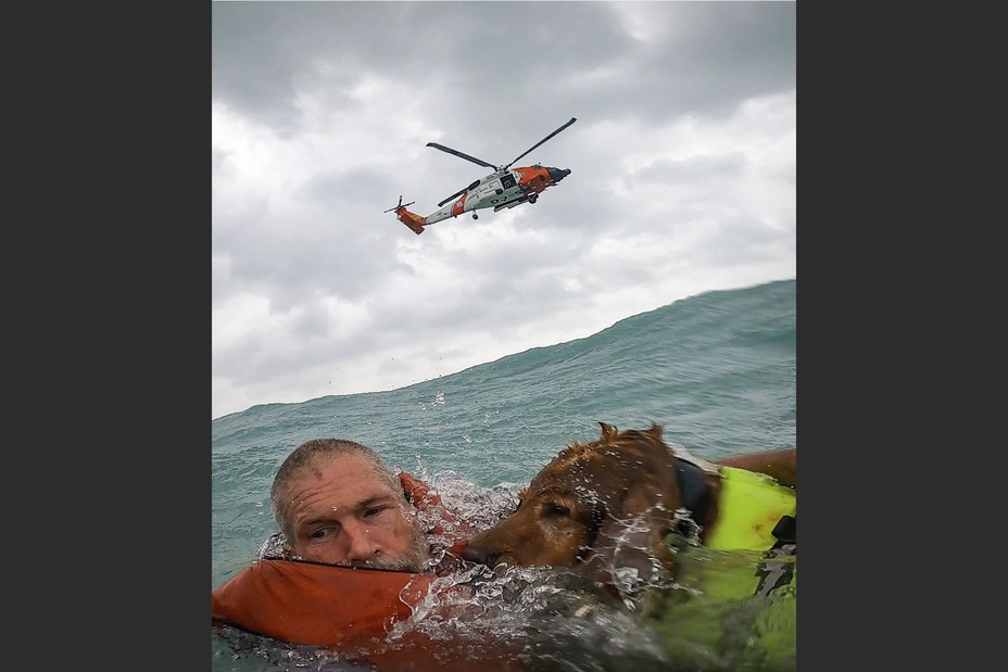 A man and his dog are rescued by the U.S. Coast Guard after his sailboat became disabled during Hurricane Helene, floating approximately 25 miles off Sanibel Island, Florida, on September 26, 2024.