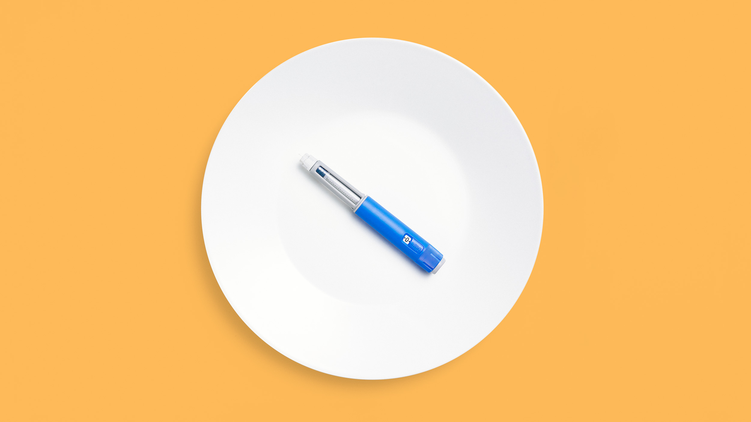 A blue Ozempic sits on a white plate on an orange background