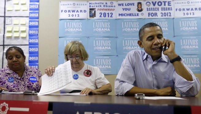 Two women sit next to Obama who is speaking on the phone