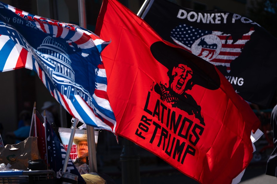 Flags wave in the air, one says 'Latinos for Trump'