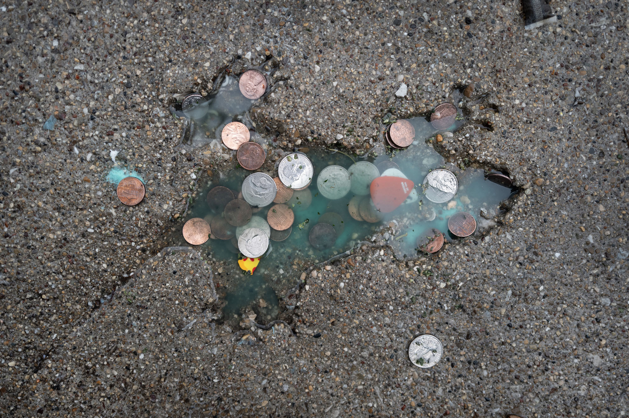 Coins are left behind by visitors at the Chicago Rat Hole, a rat-shaped impression on a sidewalk in Illinois.