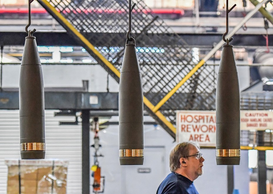 Three projectiles hand in a line as a man walks behind them in a warehouse