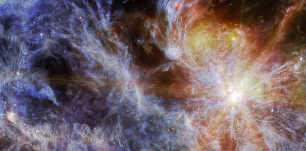 A bright young star within a colorful cloud-like nebula. The star is the brightest spot, dominating the right side of the image, surrounded by six large spokes of light that cross the image.