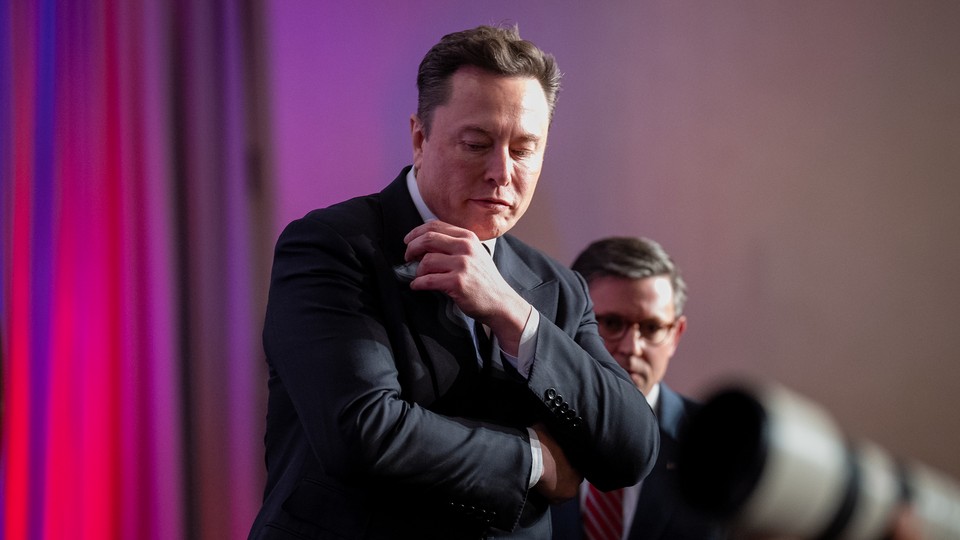 Elon Musk looks down while standing in front of House Speaker Mike Johnson