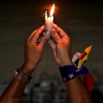 A woman holds a candle at a vigil in honor of Venezuelans detained during protests challenging the presidential election results, Caracas, December 17.