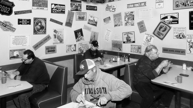 People eat alone at separate tables in a diner