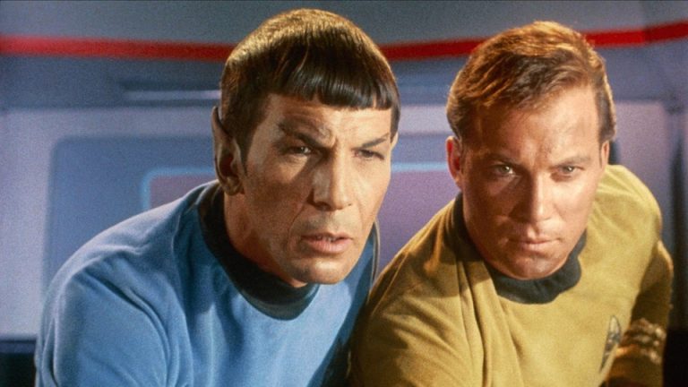 Spock and Captain James T. Kirk lean in to look intently at a screen