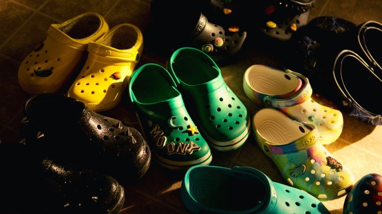 A photograph of eight pairs of yellow, green, and black crocs in an entryway.