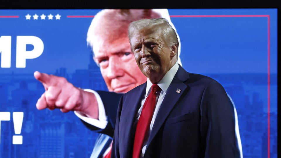 Donald Trump smiles in front of a sign that shows him pointing