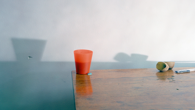 A cup sits on a desk next to a pen