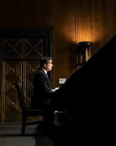 John Ratcliffe sits at a table in a low-lit, wood-paneled room.