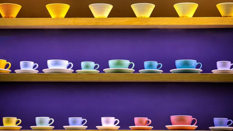 Rows of colorful coffee cups and glasses on shelves