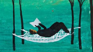 A woman reads a book while resting on a hammock between trees