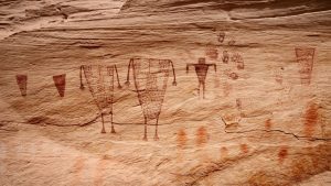 drawings of figures, shapes and handprints on a cliff wall